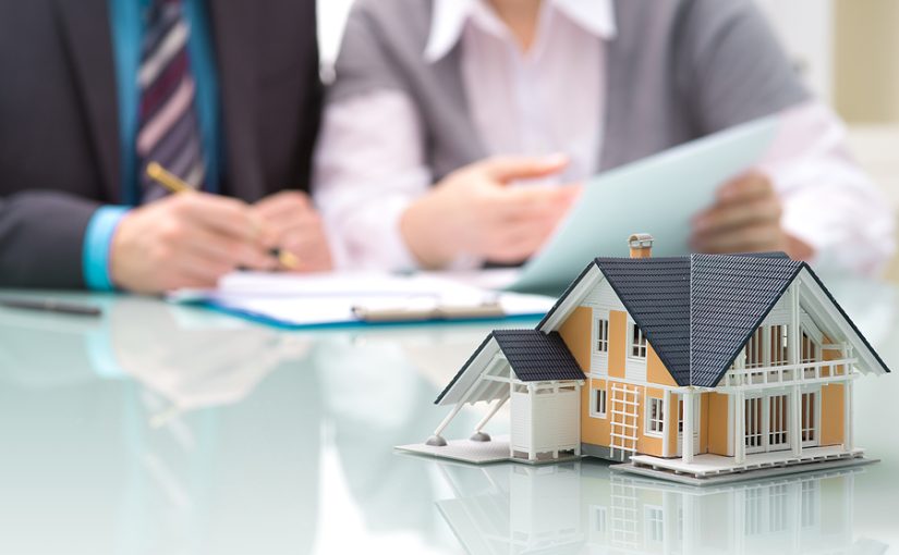 Insurance agent and homeowner go over a homeowners insurance policy with model house in foreground.