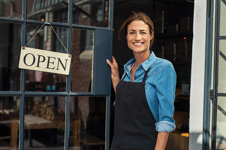 Small Business Owner opening the door of their shop with an open sign.