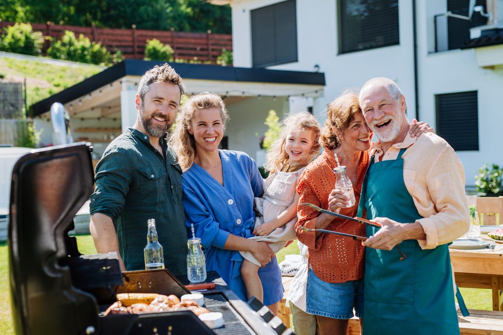 Family party with children and BBQ grill at a house.