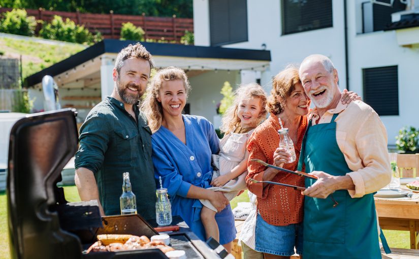 Family party with children and BBQ grill at a house.