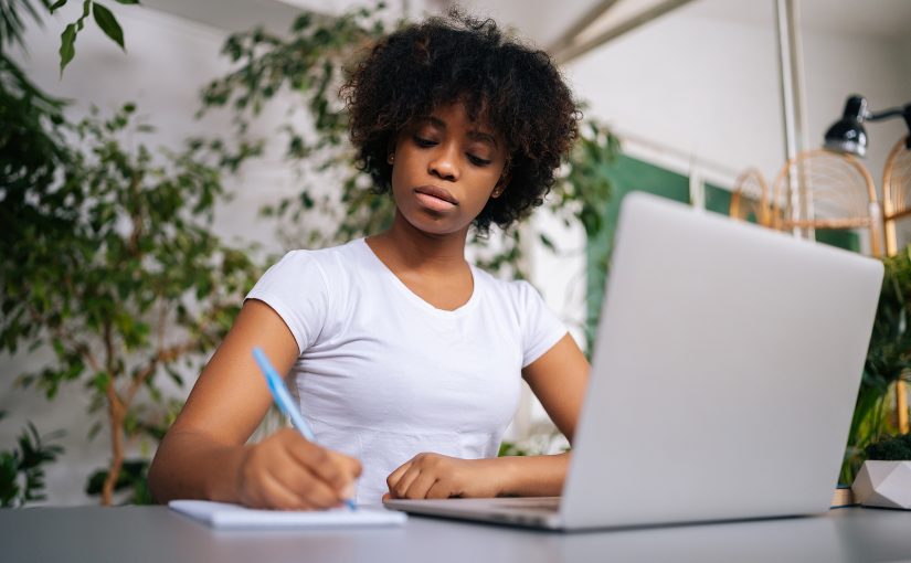 Woman in house taking a home inventory with use of a notepad and laptop.