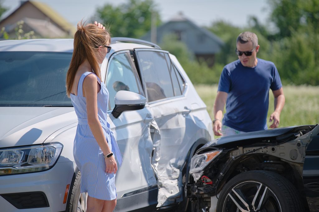 A man and women talk besides their cars involved in an auto accident.