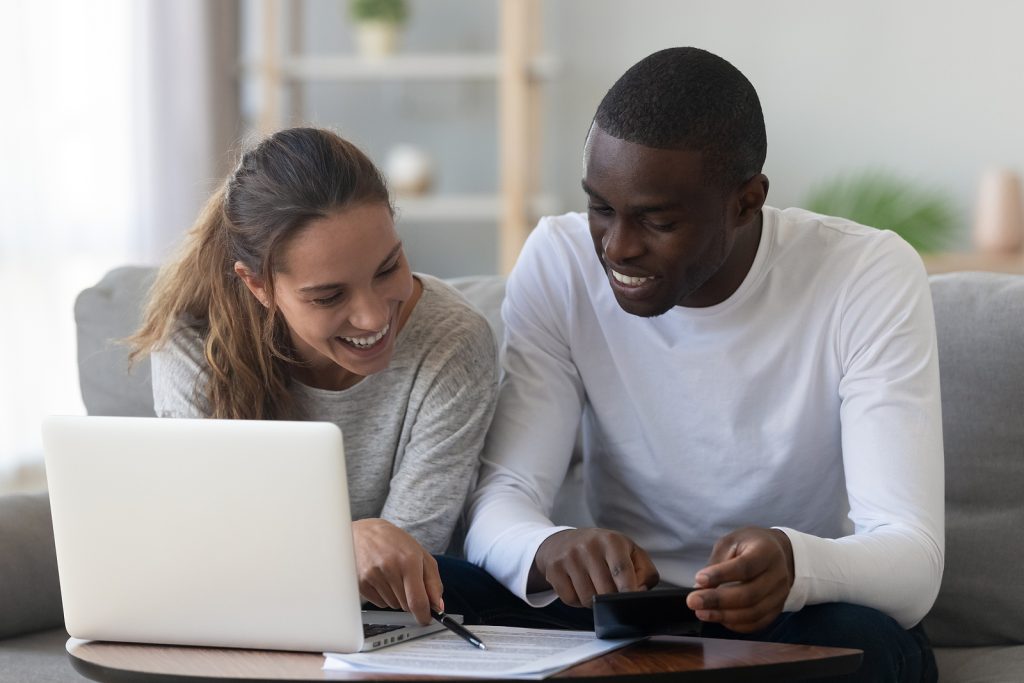 Smiling couple at home reviews documents on couch.