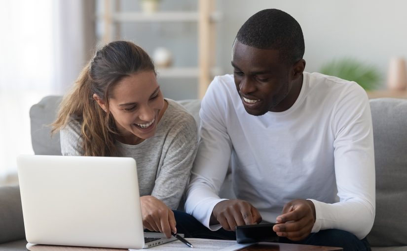 Smiling couple at home reviews documents on couch.