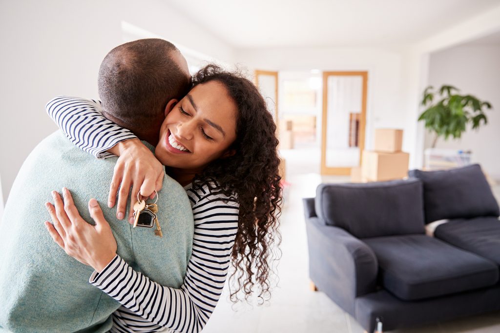 First-time homebuyers hugging inside their new home.