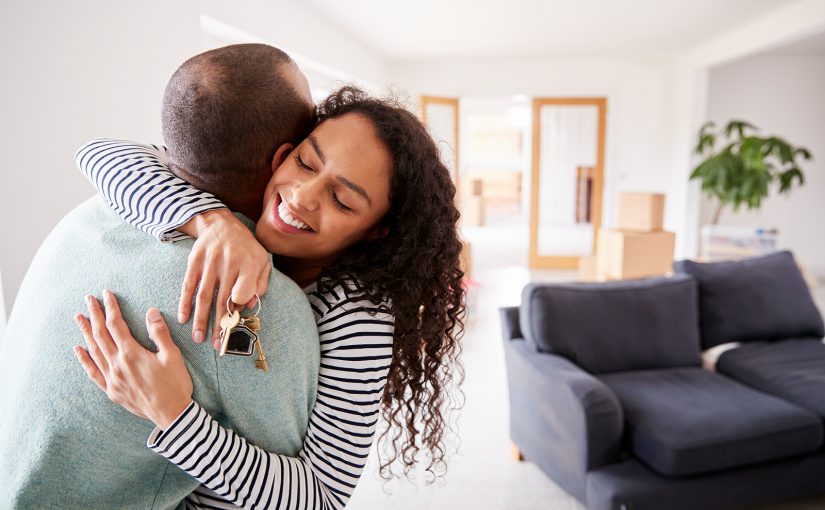 First-time homebuyers hugging inside their new home.