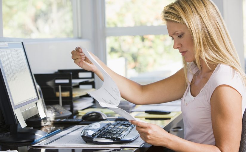 Woman in home office looking at insurance premium.