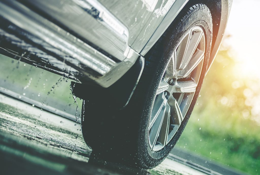 Closeup of the front of a car driving in the rain.