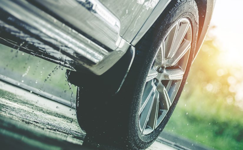 Closeup of the front of a car driving in the rain.