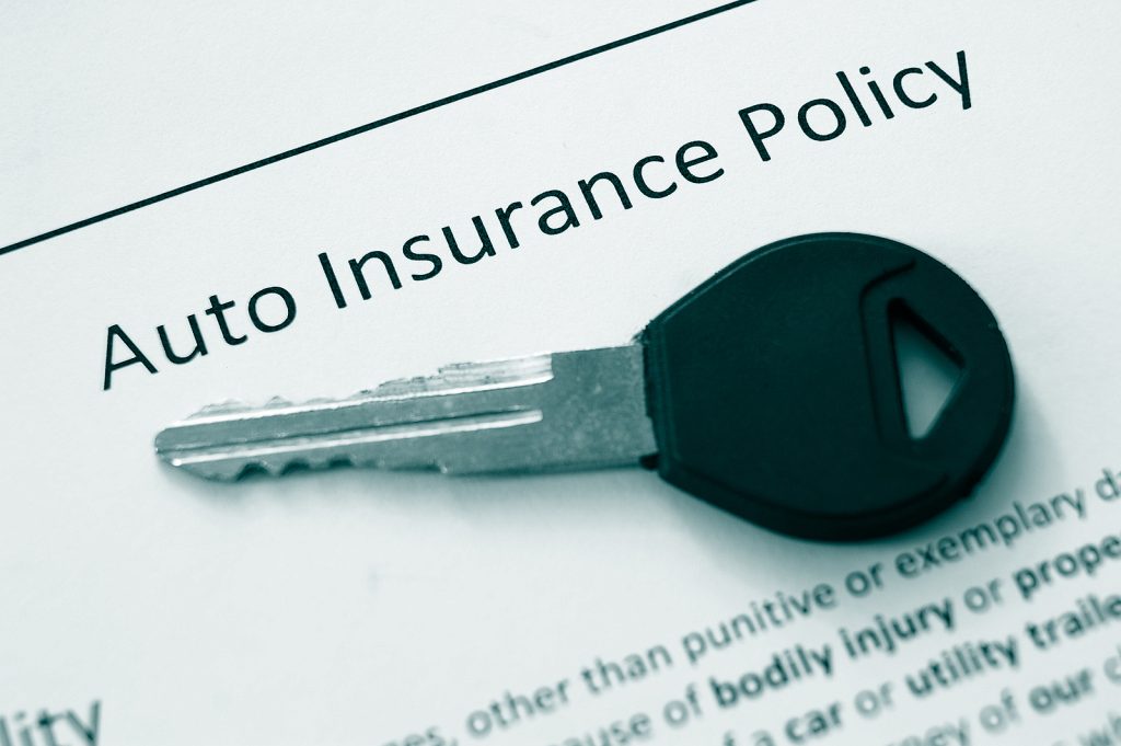 Car key on top of auto insurance policy documents