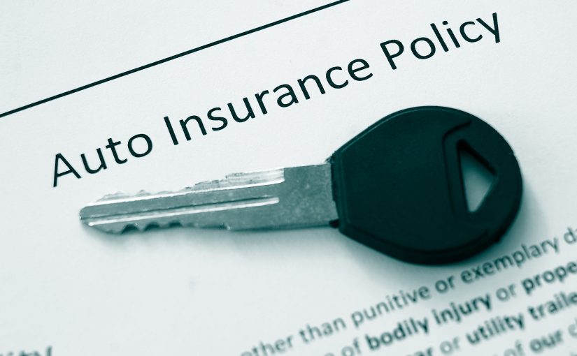 Car key on top of auto insurance policy documents