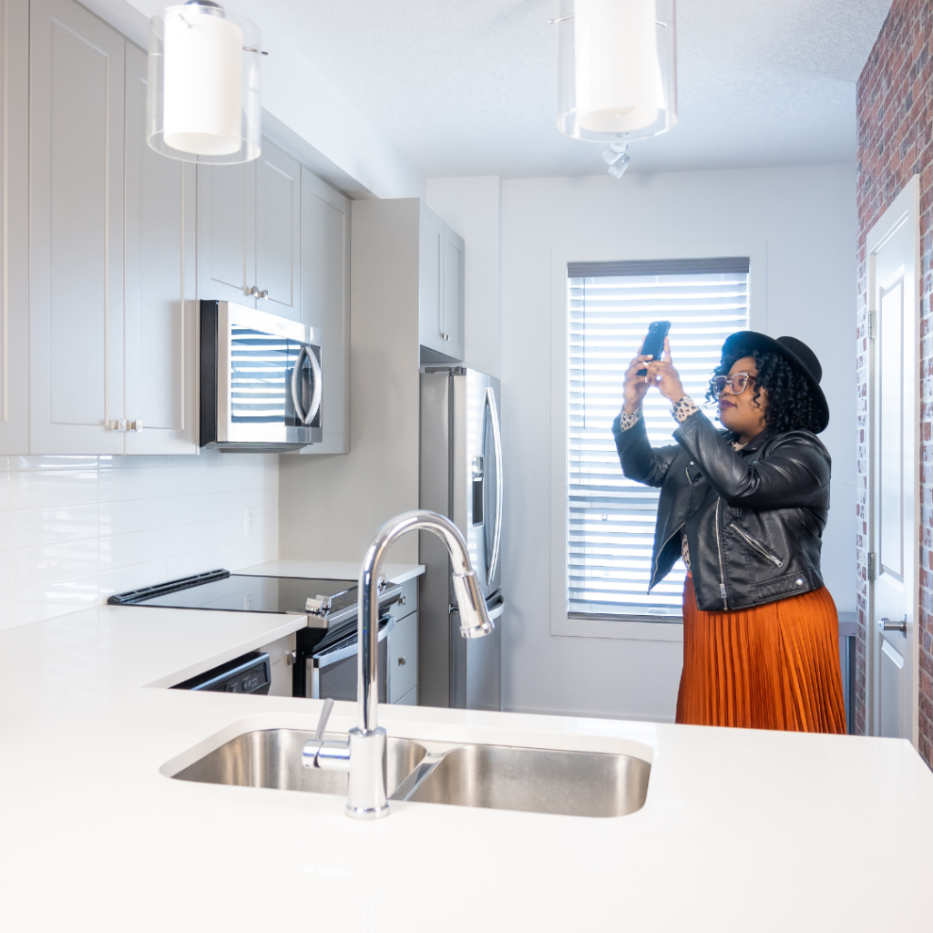 Woman taking a home inventory by taking pictures of her kitchen cabinets.