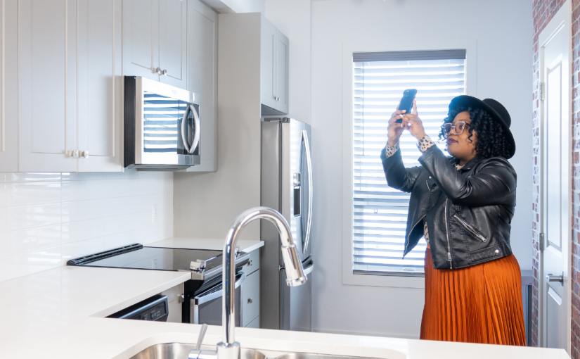 Woman taking a home inventory by taking pictures of her kitchen cabinets.