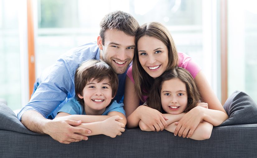 Family happily relaxing on a sofa.